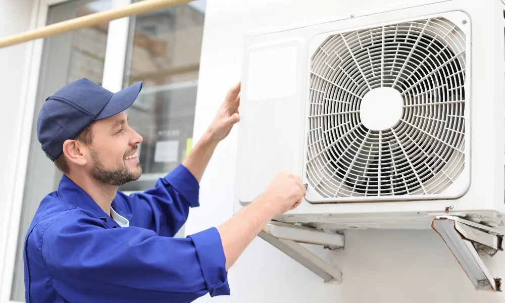 Smiling professional technician fixing the fan of air conditioner