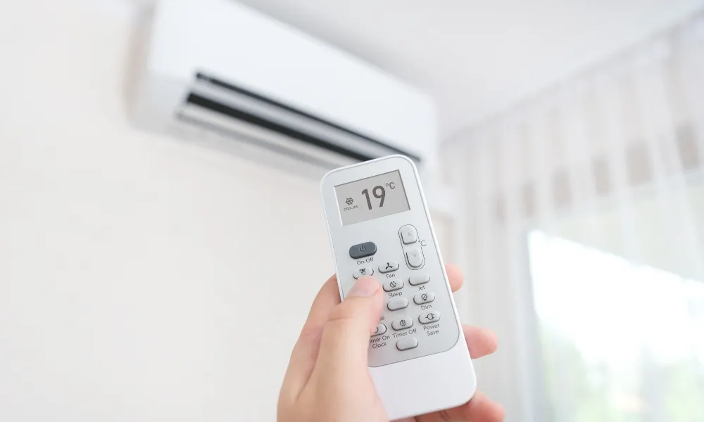 Hand holding a remote control of air conditioner and set to 19 degree celsius
