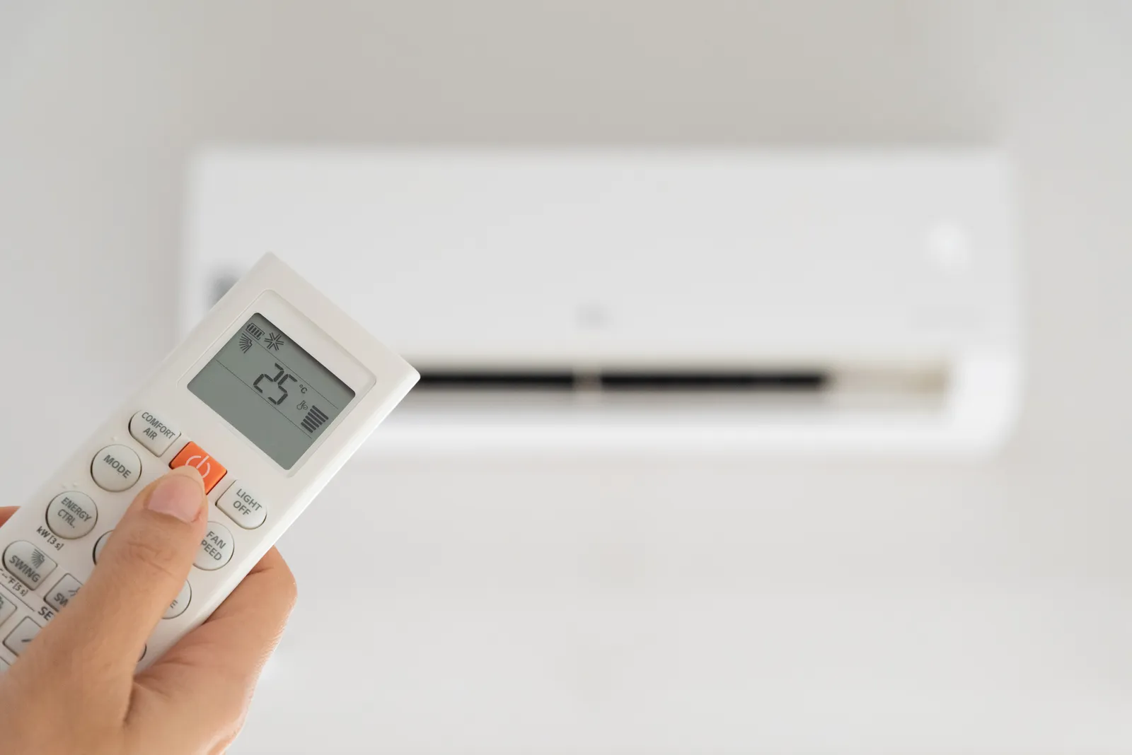woman,hand,holding,remote,controller,directed,on,the,air,conditioner